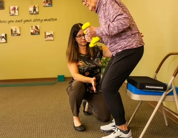 Inside the Motion Matters clinic: a therapist working one-on-one with a patient against the yellow wall