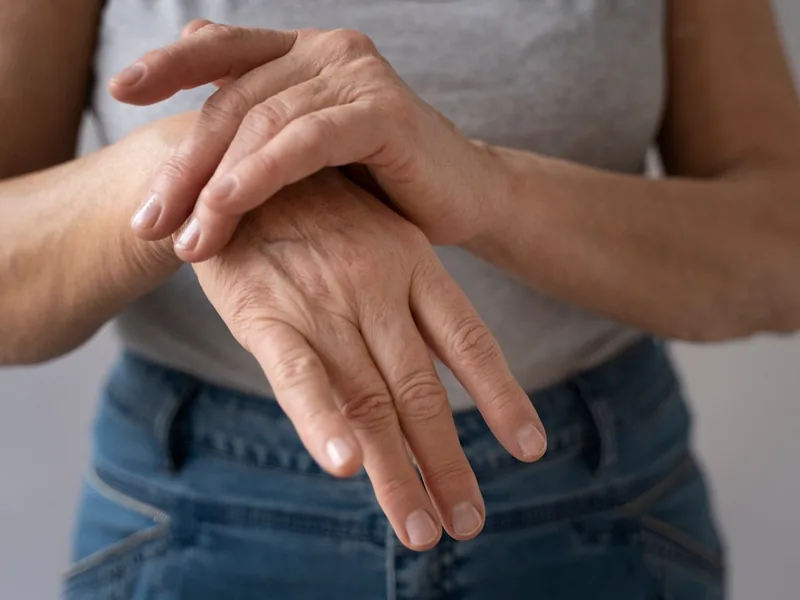 Close-up of one hand rubbing the fingers and joints of the other