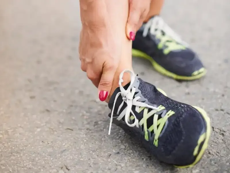 A runner reaching down to hold the heel of their shoe