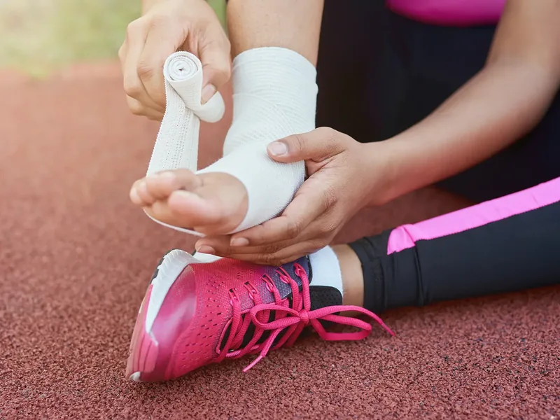 A young athlete&rsquo;s ankle being taped on a running track