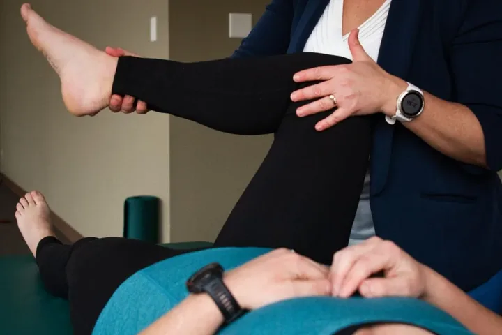 A Motion Matters therapist mobilising a patient's leg on a treatment table