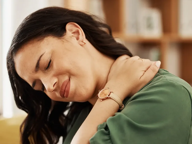 A woman wincing with her hand on the side of her neck, the kind of pain the first phase calms down