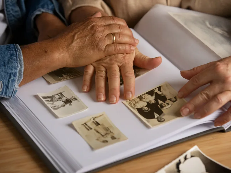 Two pairs of hands turning the pages of a photo album, the kind of imagery work used in graded motor imagery