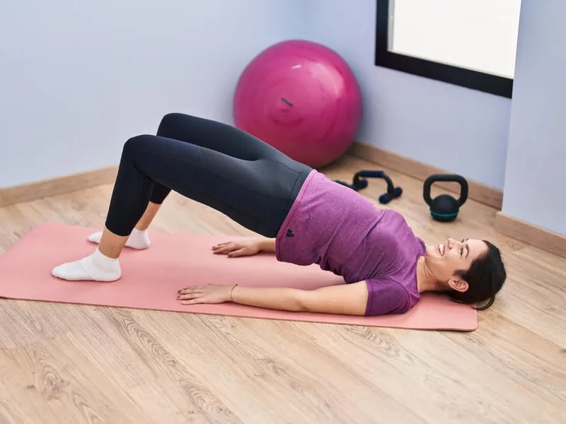 A person holding a bridge position on an exercise mat, a core exercise used in pelvic floor therapy