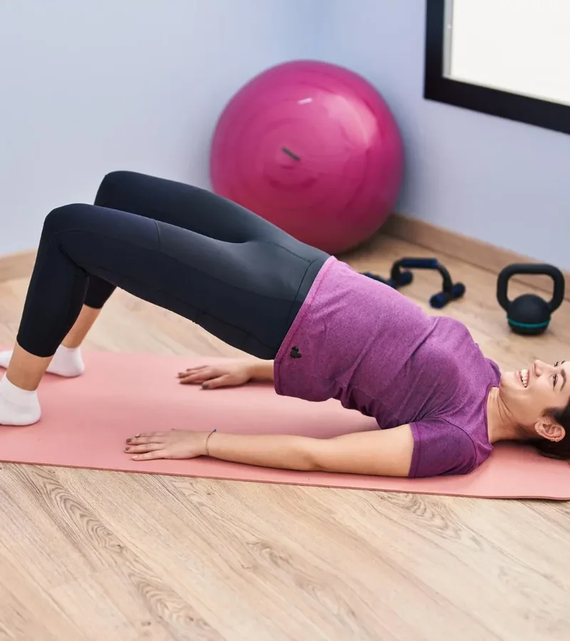 A person holding a bridge position on an exercise mat, a core exercise used in pelvic floor therapy